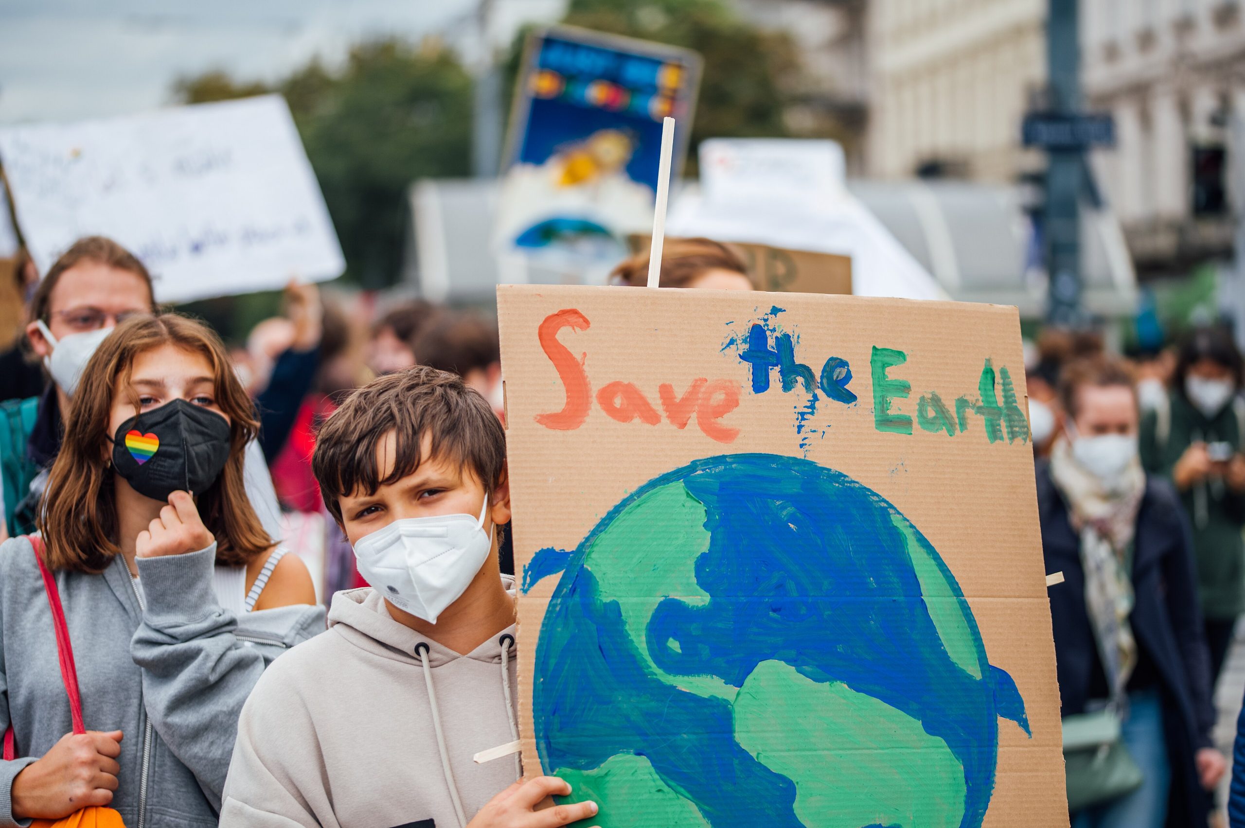 Jonge demonstrant tijdens de Global Climate Strike, september 2021 (Foto: Ivan Radic, <a href='https://commons.wikimedia.org/wiki/File:Young_protester_at_Global_Climate_Strike_holding_a_banner_with_the_message_%22Save_the_Earth%22_%2851523933362%29.jpg' target='_blank'>Wikimedia Commons</a>)